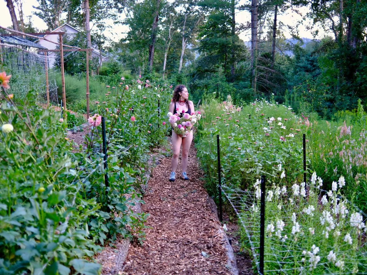 woman in blue dress on flower farm with dahlias