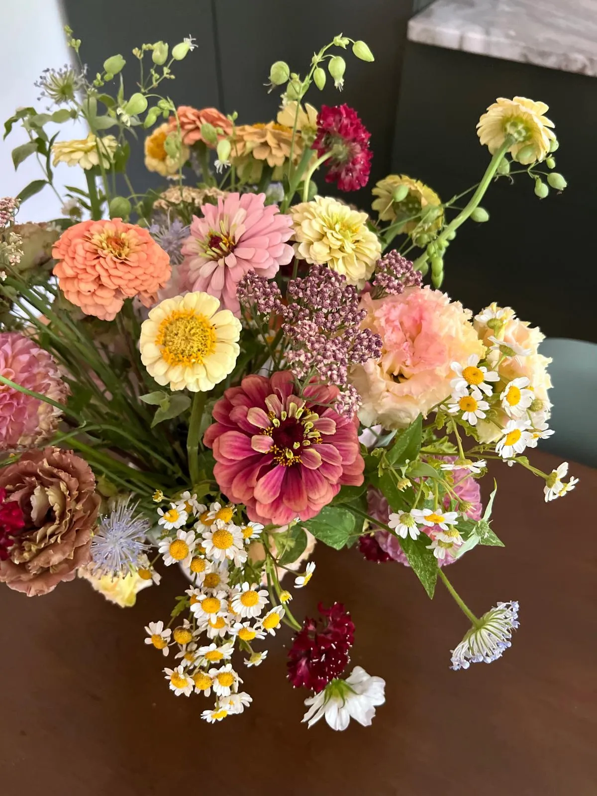 a lush bouquet of zinnias and other flowers on a wood table